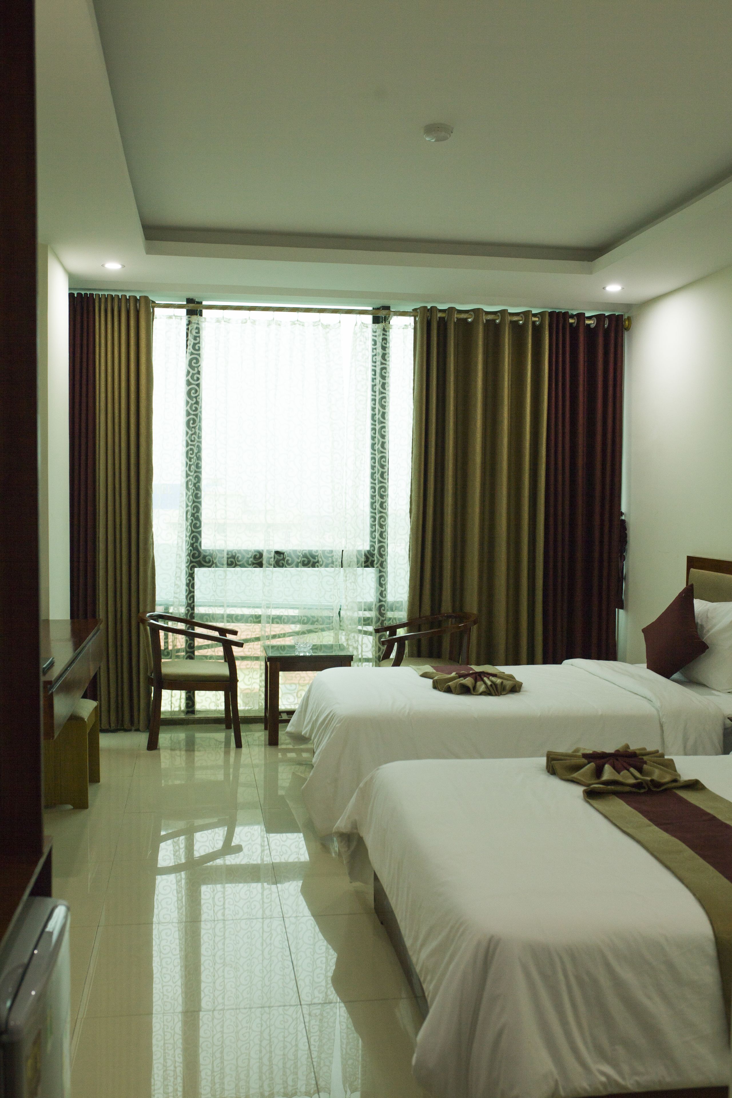 A hotel room with two beds, a desk, and a chair.