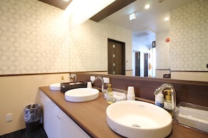 A hotel bathroom with two sinks, a mirror, and a trash bin. - Sejour Inn Capsule (Hiroshima)