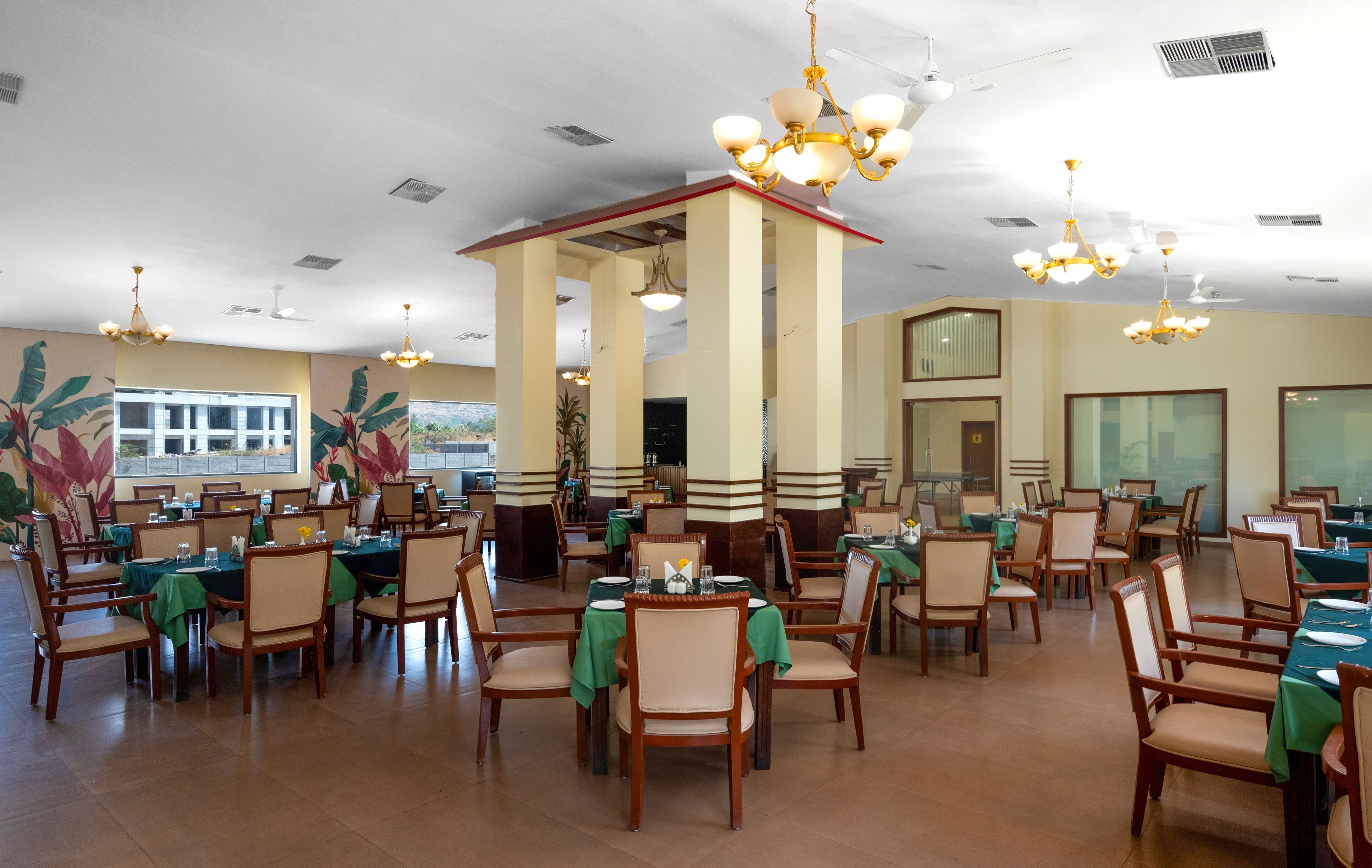 A spacious dining area with multiple tables and chairs, ceiling fans, and decorative lighting fixtures.