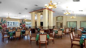 A spacious dining area with multiple tables and chairs, ceiling fans, and decorative lighting fixtures.