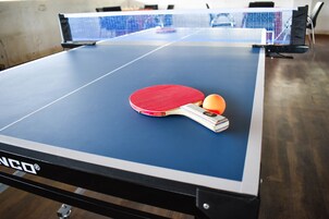 A ping pong table with a red paddle and a ball, and a net in the background.