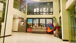 A spacious lobby with a high ceiling, a modern chandelier, a sofa, and a large window overlooking the interior. - Altabriza Resort Boracay (Boracay Island)