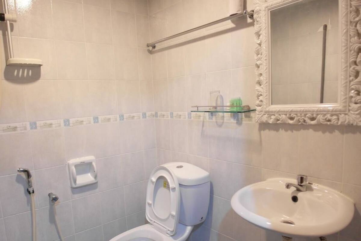 A bathroom with a toilet, sink, mirror, and shower.