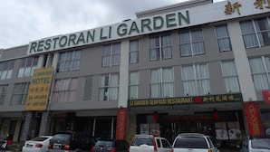 A building with a sign reading "Restoran Li Garden" and another sign for a seafood restaurant. There are cars parked in front. - Li Garden Hotel (Pasir Gudang)