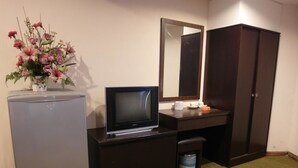 A hotel room with a small desk, a television, a mirror, a wardrobe, a trash bin, and a flower vase. - Li Garden Hotel (Pasir Gudang)