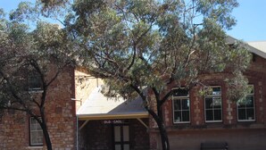 Un bâtiment historique à la façade en pierre, doté d’un porche et d’une enseigne indiquant « Ancien CAOL ».