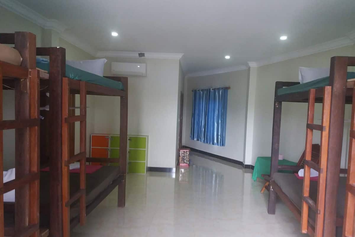 Quarto com beliches, um armário verde e um aparelho de ar condicionado na parede.