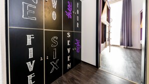 A hallway with black walls featuring large white and purple numbers from one to eight. - Adagio Hostel Basilica (Budapest)