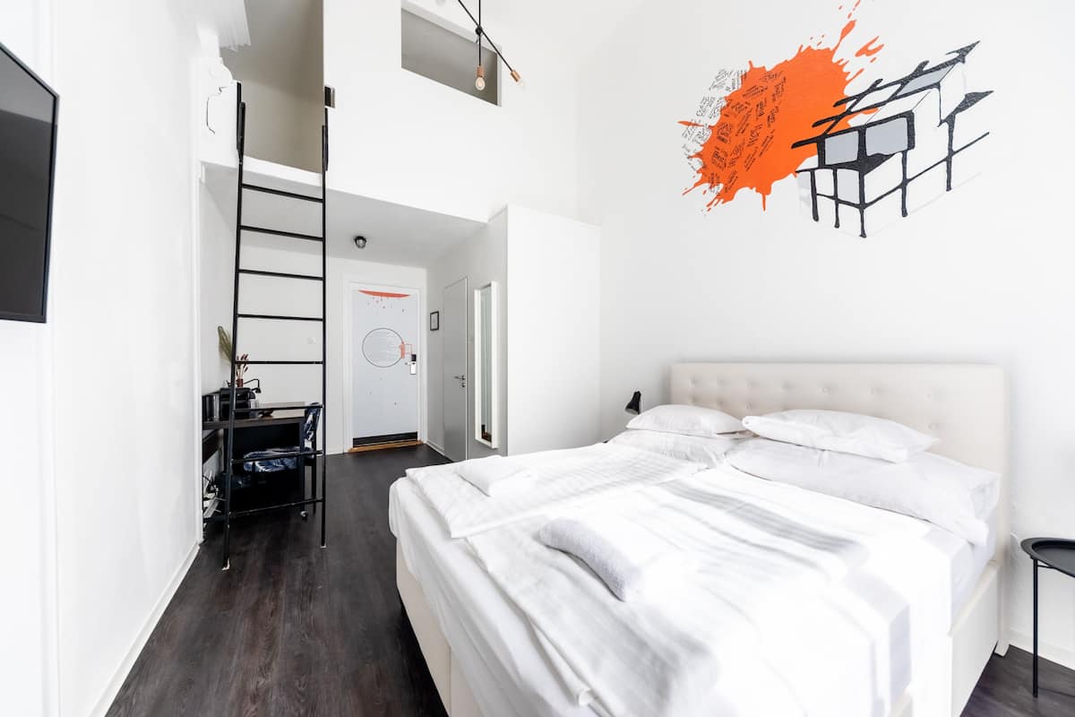 A bedroom with a bunk bed, a desk with a chair, and a ladder.