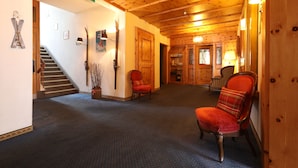 A wooden-floored hallway with a staircase, a red chair, and a wooden door. - Hotel Concordia Davos (Davos)