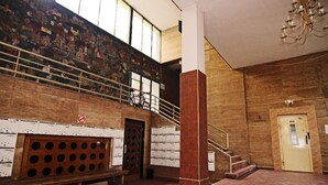 Un vestíbulo espacioso con una escalera, un mural en la pared y una araña.