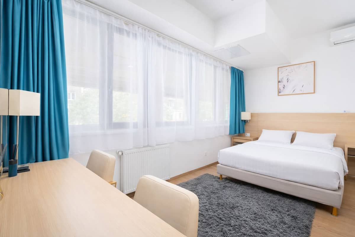 A hotel room with a bed, a desk, and a chair.