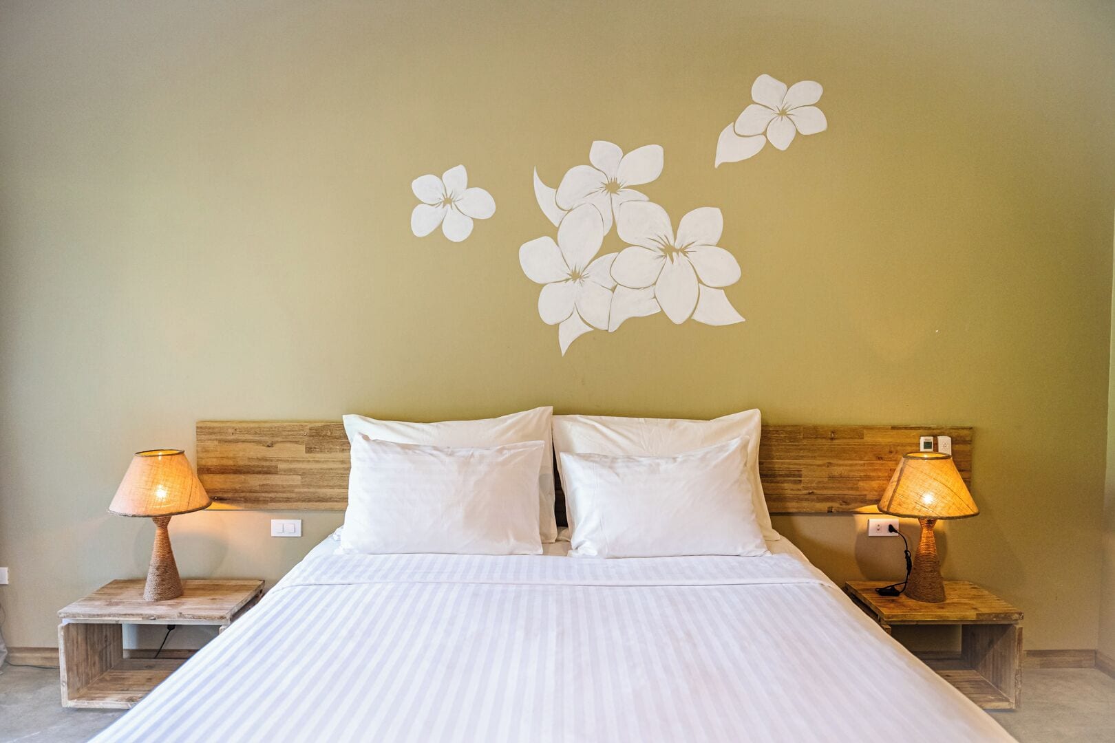 A bedroom with a bed, two bedside tables, two lamps, and wall art.