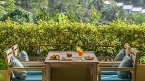 A table with two chairs, a glass of orange juice, and a bowl of fruit. - Lahana Resort Phu Quoc & Spa (Phu Quoc)
