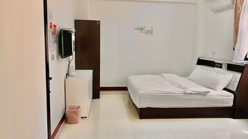 Un dormitorio con una cama, un televisor, un armario pequeño y una pared con una cita motivacional.