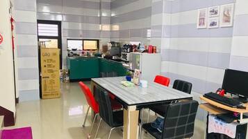 A modern kitchen with a dining area, including a table with chairs, a computer setup, and a refrigerator.
