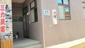 A two-story building with a brick facade, a visible entrance, and a small outdoor area with potted plants. - Sanli B&B (Jinhu)