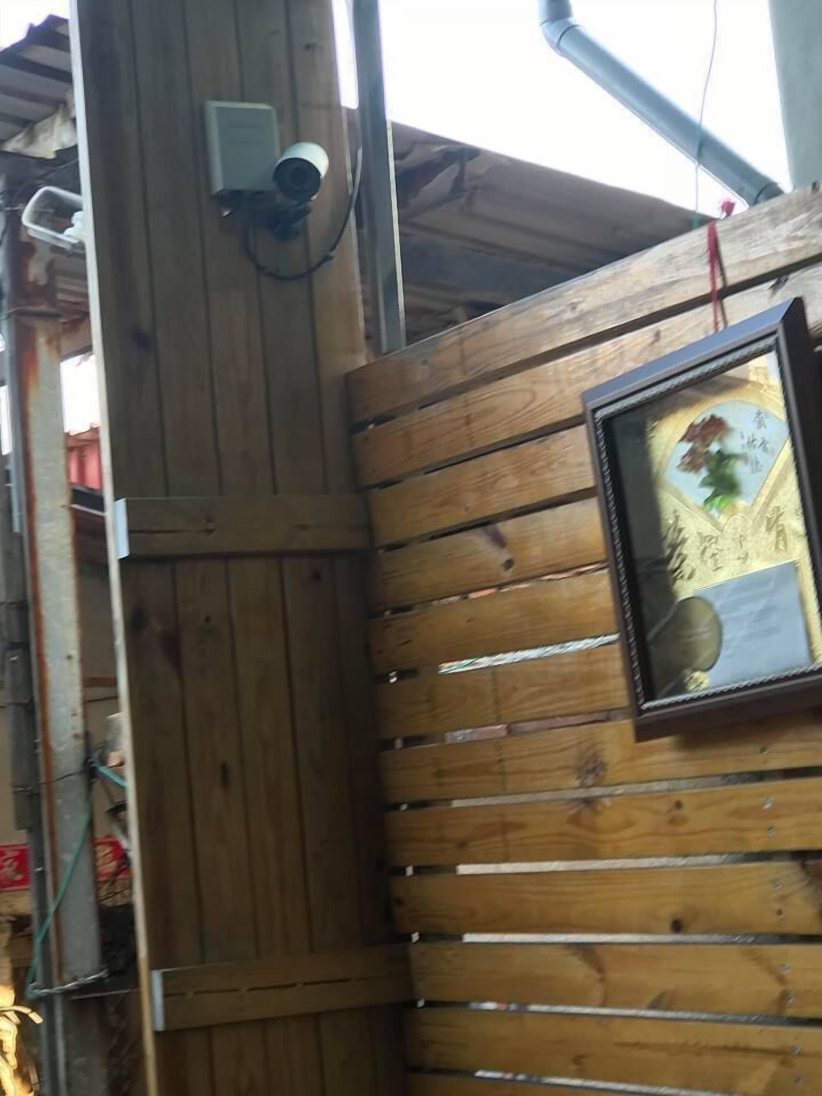 Paret de fusta amb un quadre encadrats i una càmera de seguretat.