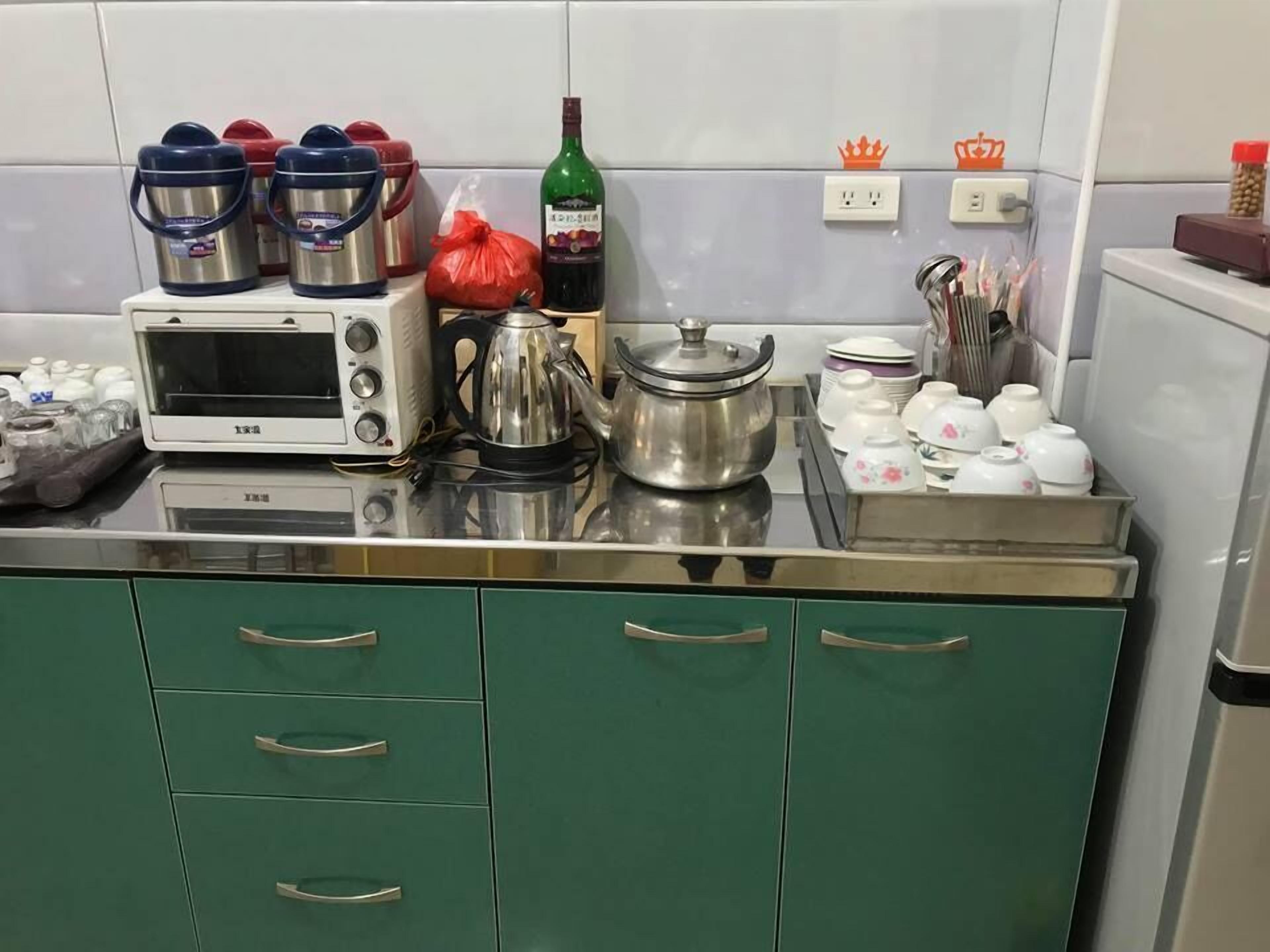 A kitchen with a microwave, kettle, and various containers on the counter.