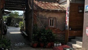 A narrow alleyway with a small brick building, potted plants, and a bicycle. - Sanli B&B (Jinhu)