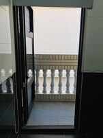 Un estrecho acceso que da a un balcón con suelo de baldosas y barandilla blanca.