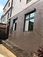 Un edificio con fachada de ladrillo, amplias ventanas y un banco de madera a un lado.