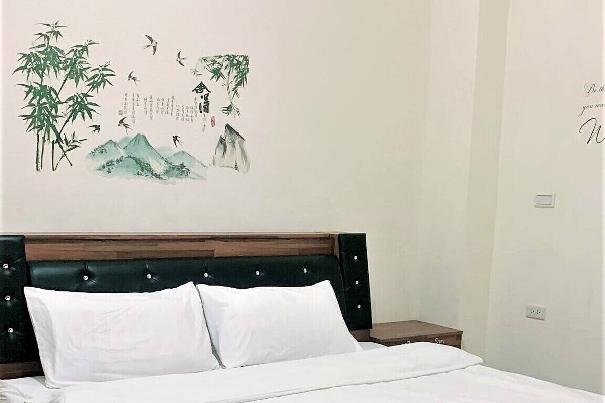 A neatly made bed with white linens in a room with a wooden headboard.