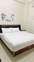 Una cama bien hecha con sábanas blancas en una habitación con cabecera de madera.