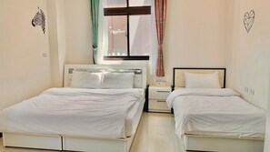 Habitación de hotel con dos camas individuales, una mesita de noche, una ventana con cortinas y un adhesivo en la pared.