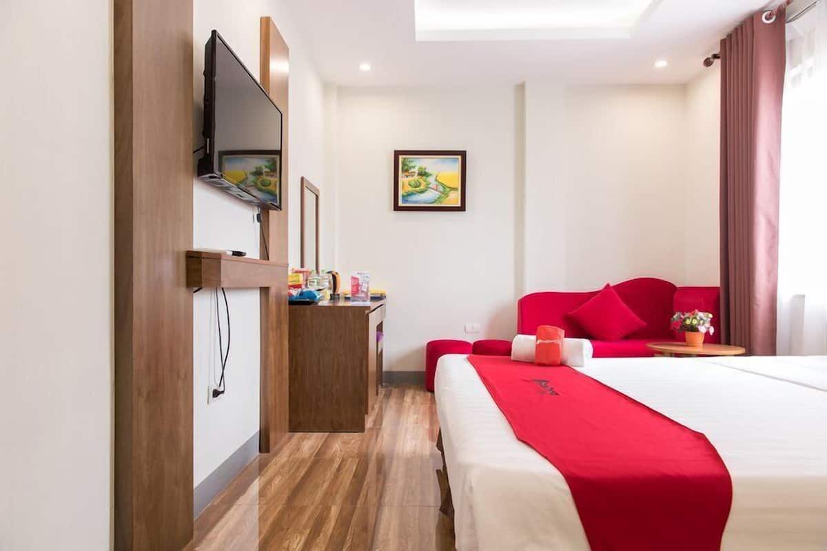 Una habitación de hotel con una cama, un escritorio, un televisor y un cuadro en la pared.