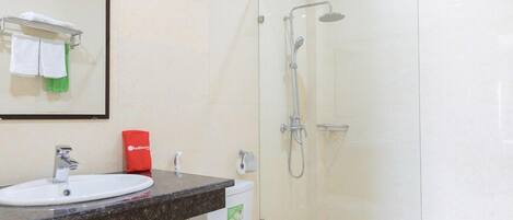 Une salle de bain équipée d’un lavabo, de toilettes et d’une douche à parois de verre.