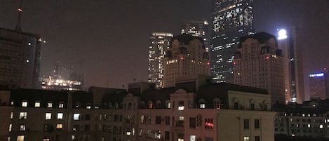 Un paisaje urbano nocturno con edificios altos iluminados y construcciones residenciales.