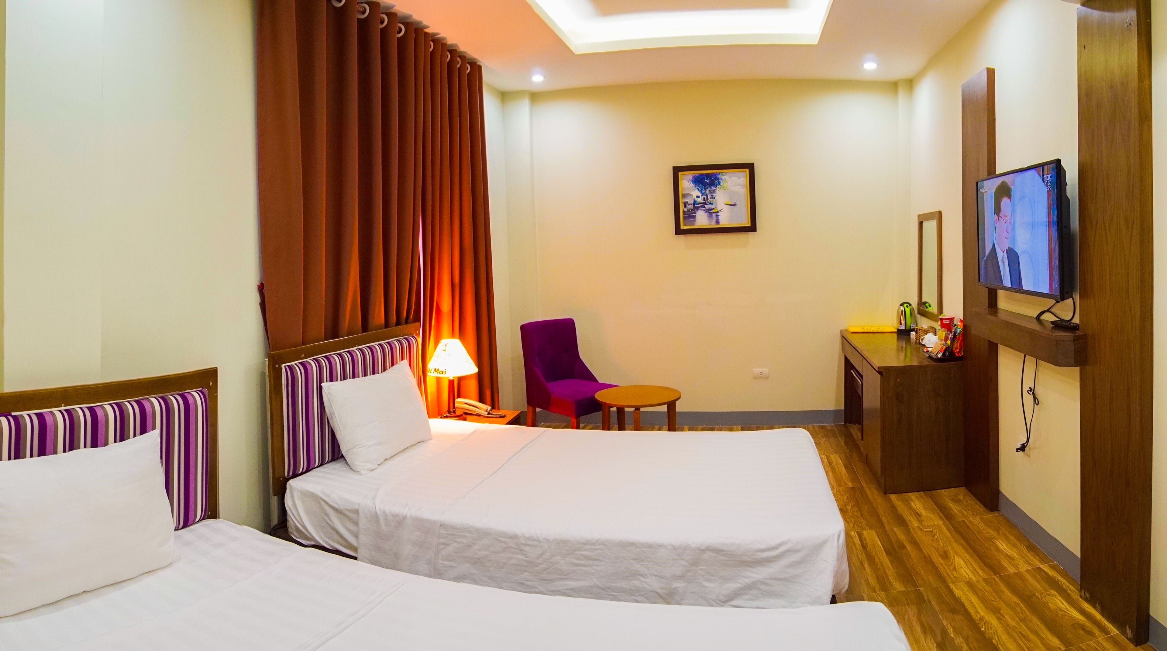 A hotel room with two beds, a desk, a chair, a television, and a painting on the wall.