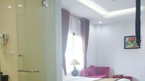 A hotel room with a bed, a glass door, a lamp, and a painting on the wall. - K Business 3 Hotel (Formerly Mai Hotel) (Hanoi)