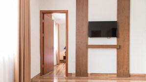 A hallway with wooden flooring, a door, and a mounted television on the wall. - K Business 3 Hotel (Formerly Mai Hotel) (Hanoi)
