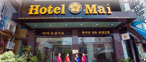 The exterior of Hotel Mai with a large sign displaying the name and a flower logo.