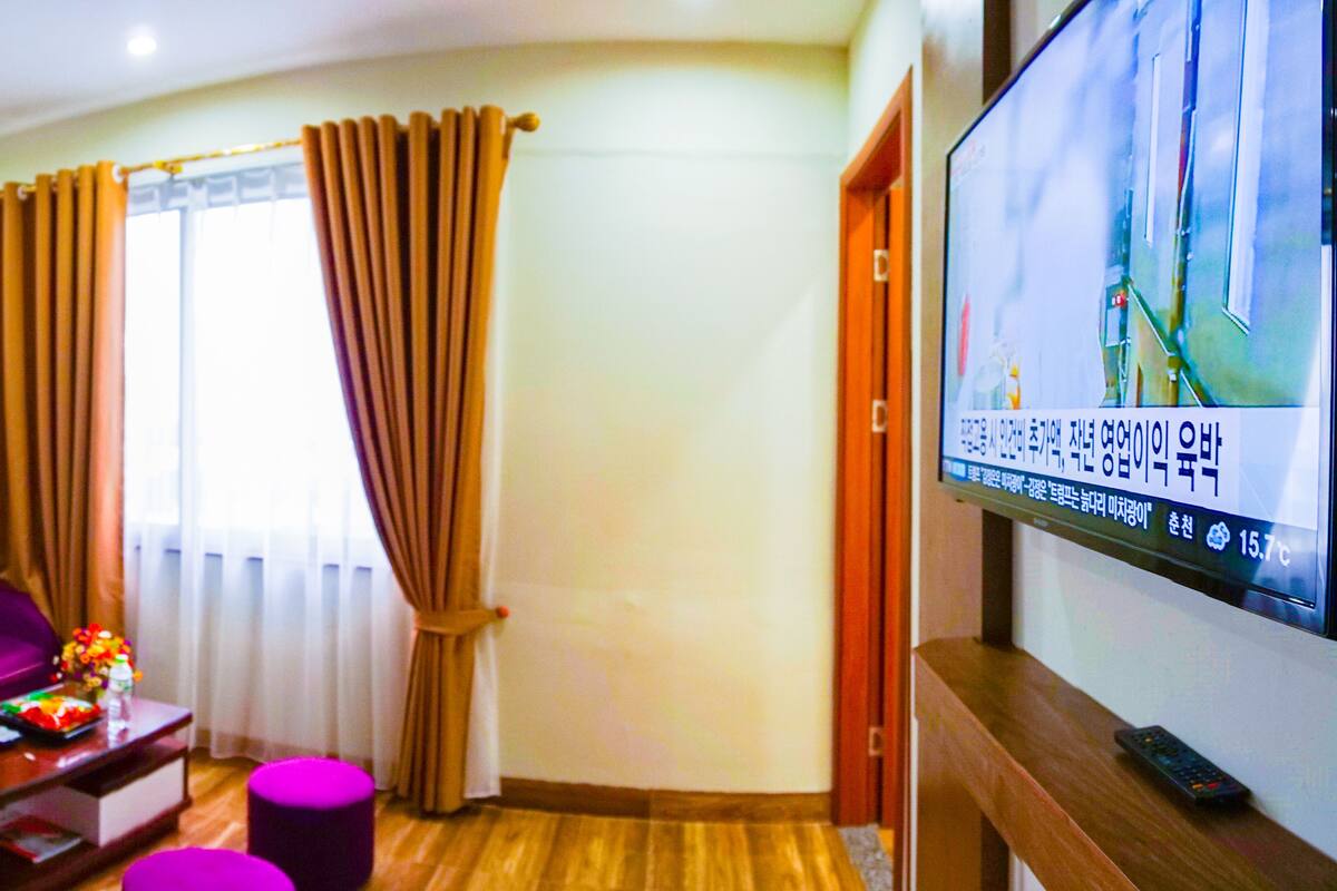 Una sala de estar con un sofá púrpura, una mesa de centro y un televisor en la pared.