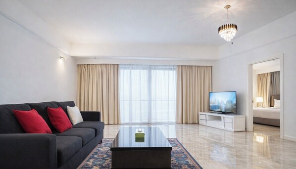 A modern living room with a sofa, a coffee table, a TV, and a chandelier.