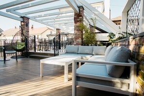 Un patio exterior con un sofá blanco, una silla colgante y una mesa.