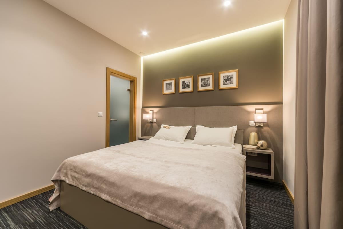 A hotel room with a bed, bedside tables, a headboard, and framed pictures on the wall.