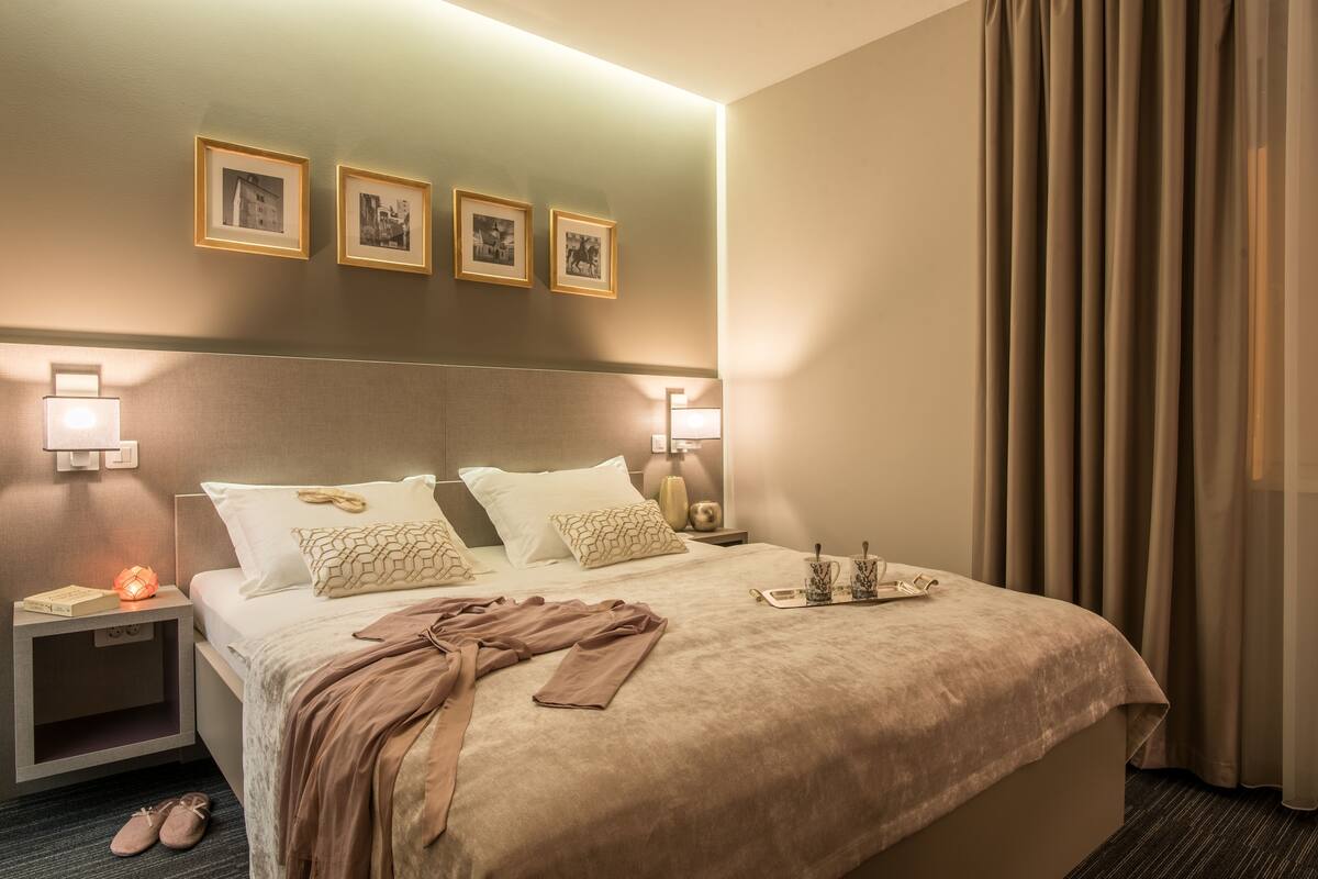 A hotel room with a large bed, bedside lamps, a nightstand, and a window with curtains.