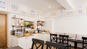 A modern kitchen with white cabinetry, wooden shelves, and a breakfast buffet setup. - Hotel Sundial (Zagreb)