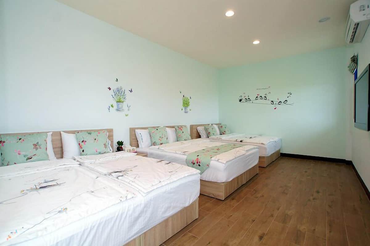 Une chambre d’hôtel avec trois lits simples, chacun doté de draps à motifs floraux et d’une tête de lit.