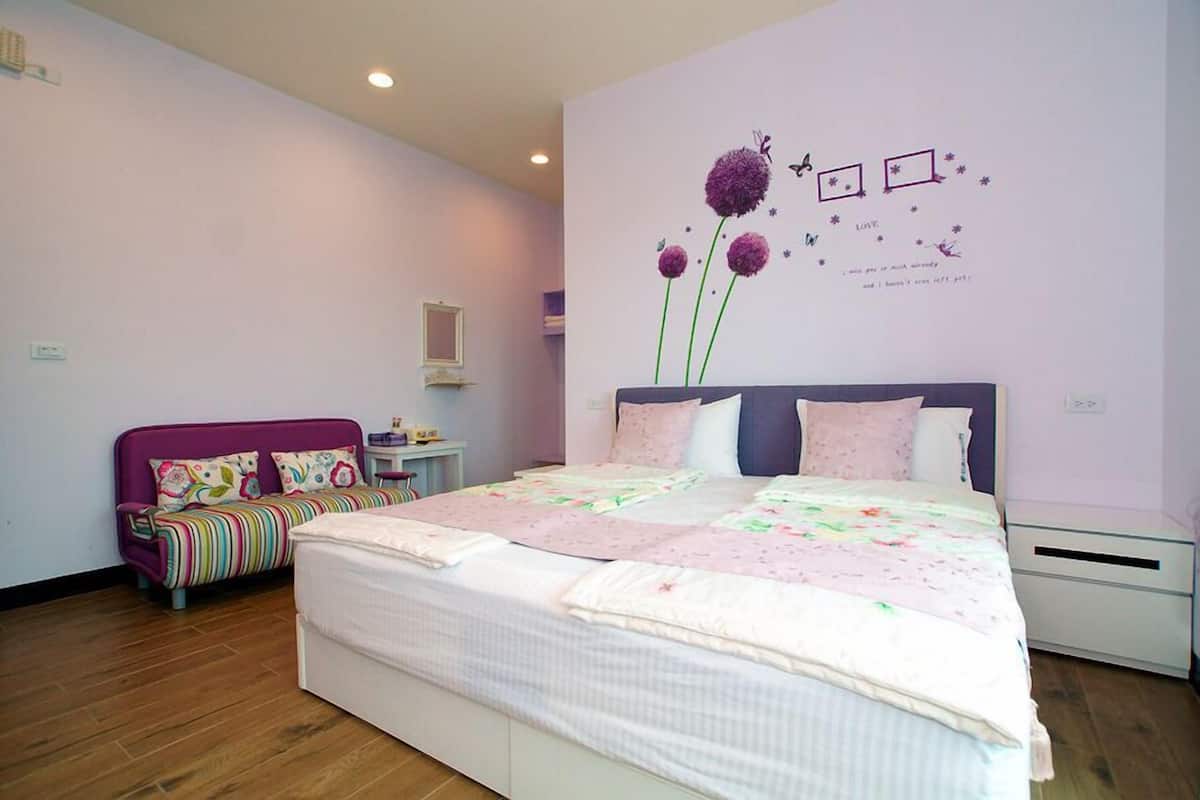 Une chambre avec un grand lit, un canapé rose et un élément décoratif mural.