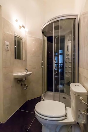 Une salle de bain moderne avec une douche à parois incurvées, des toilettes et un lavabo surmonté d’un miroir.