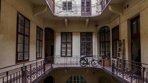 Un immeuble à plusieurs étages doté d’une cour intérieure, avec des balcons ornés de rampes en métal et un vélo garé sur l’un d’eux.
