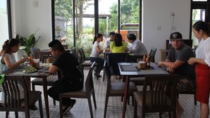 A dining area with tables and chairs, large windows, and a view of the outdoors. - Hoi An Four Season Villa (Da Nang)