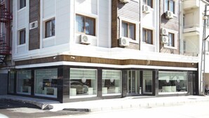 A modern building with large glass windows and air conditioning units. - Adana Omur Otel (Adana)