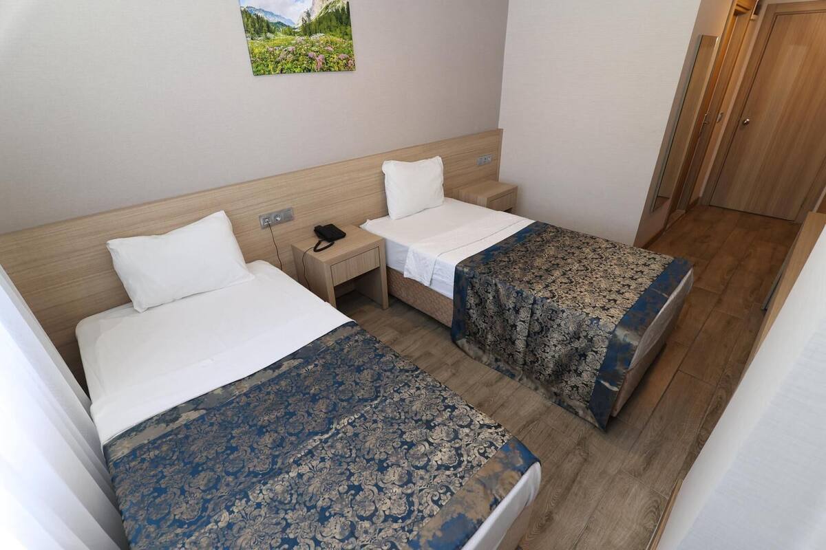 A hotel room with two beds, a nightstand, a phone, and a door.