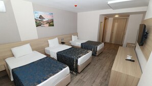 A hotel room with three beds, a desk, and a television. - Adana Omur Otel (Adana)